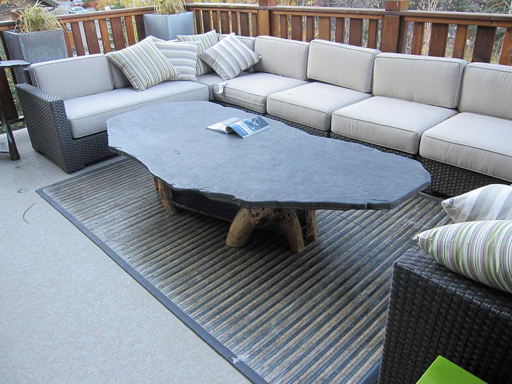 Aspen Stone coffee table with a natural stone top and wood base on a patio